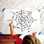 A toddler looking at spider web sticker activity.