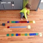 Preschooler touching magnetic tiles to count them on the line he measured.