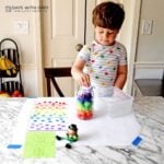A preschooler adding a purple pom pom into his Leprechaun trap.
