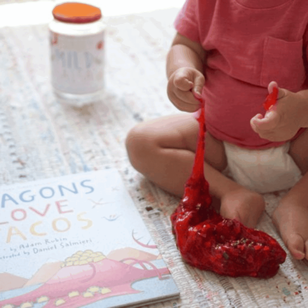 Toddler playing with slime that is called salsa slime to go with the book dragons love tacos.