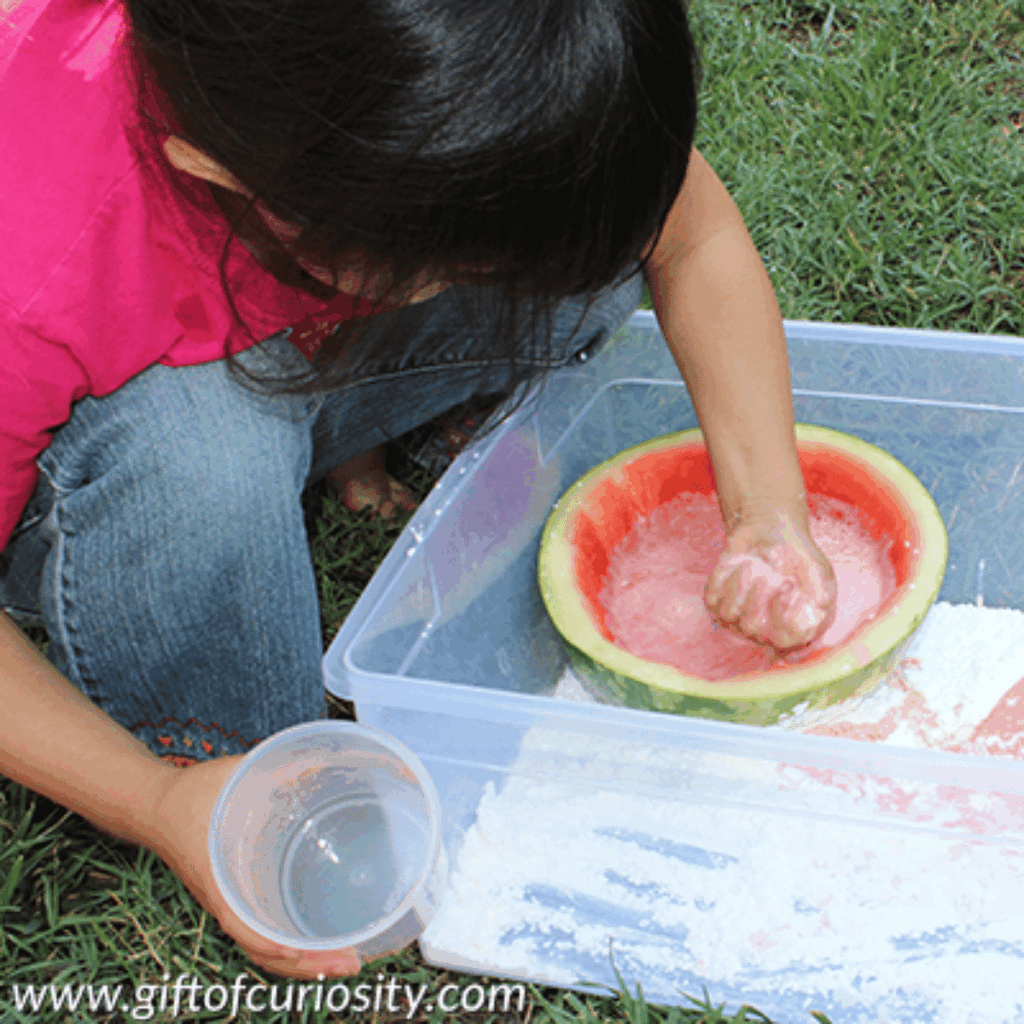 Child playing in watermelon oobleck.