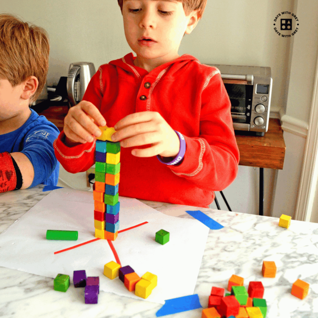 A kindergarten boy stacking small blocks.