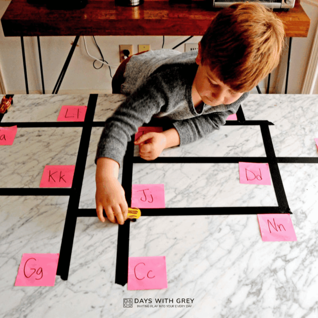 A young child sorting cars for the letter sound that the mom calls out.