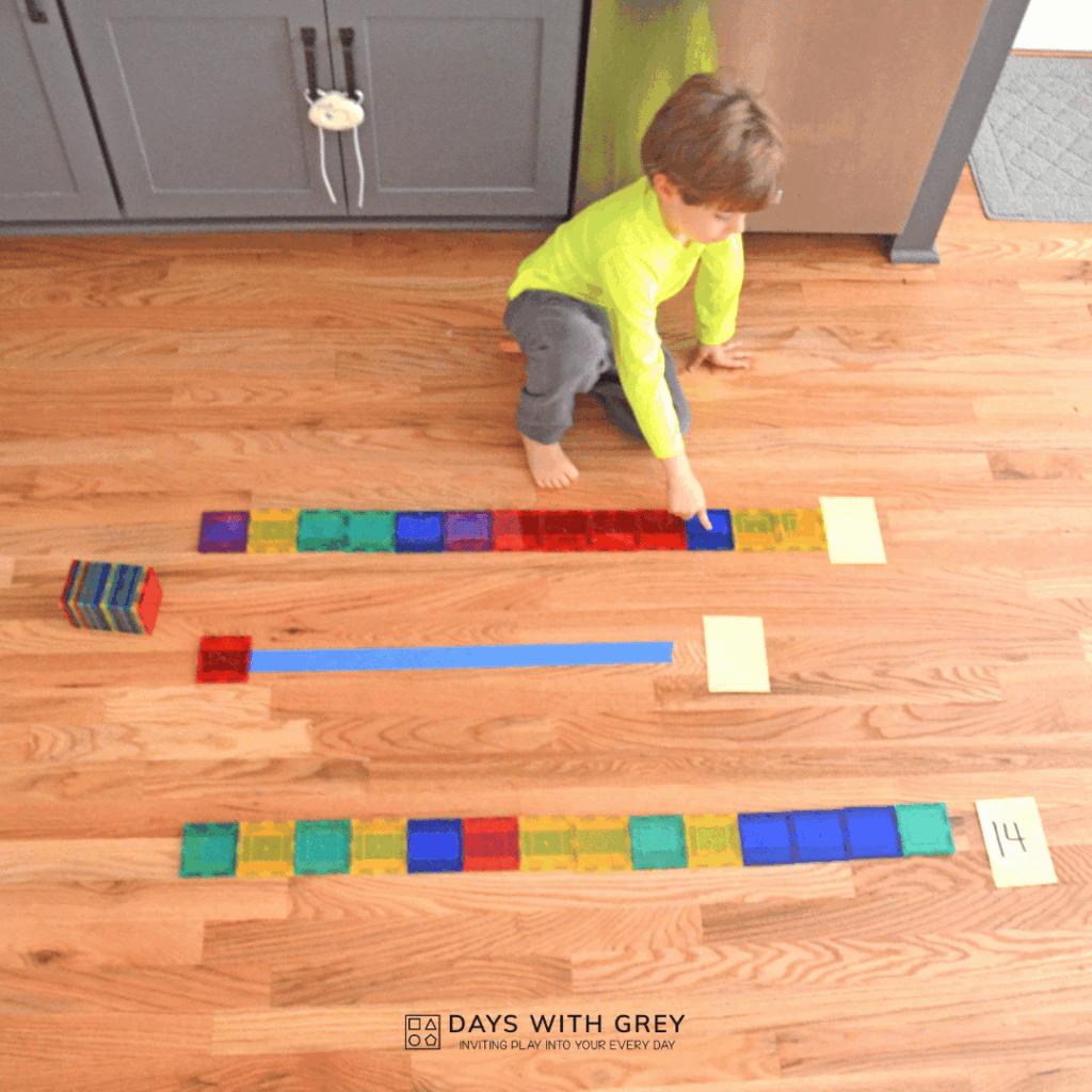 A kindergartener using magnetic tiles to measure lines on the floor.