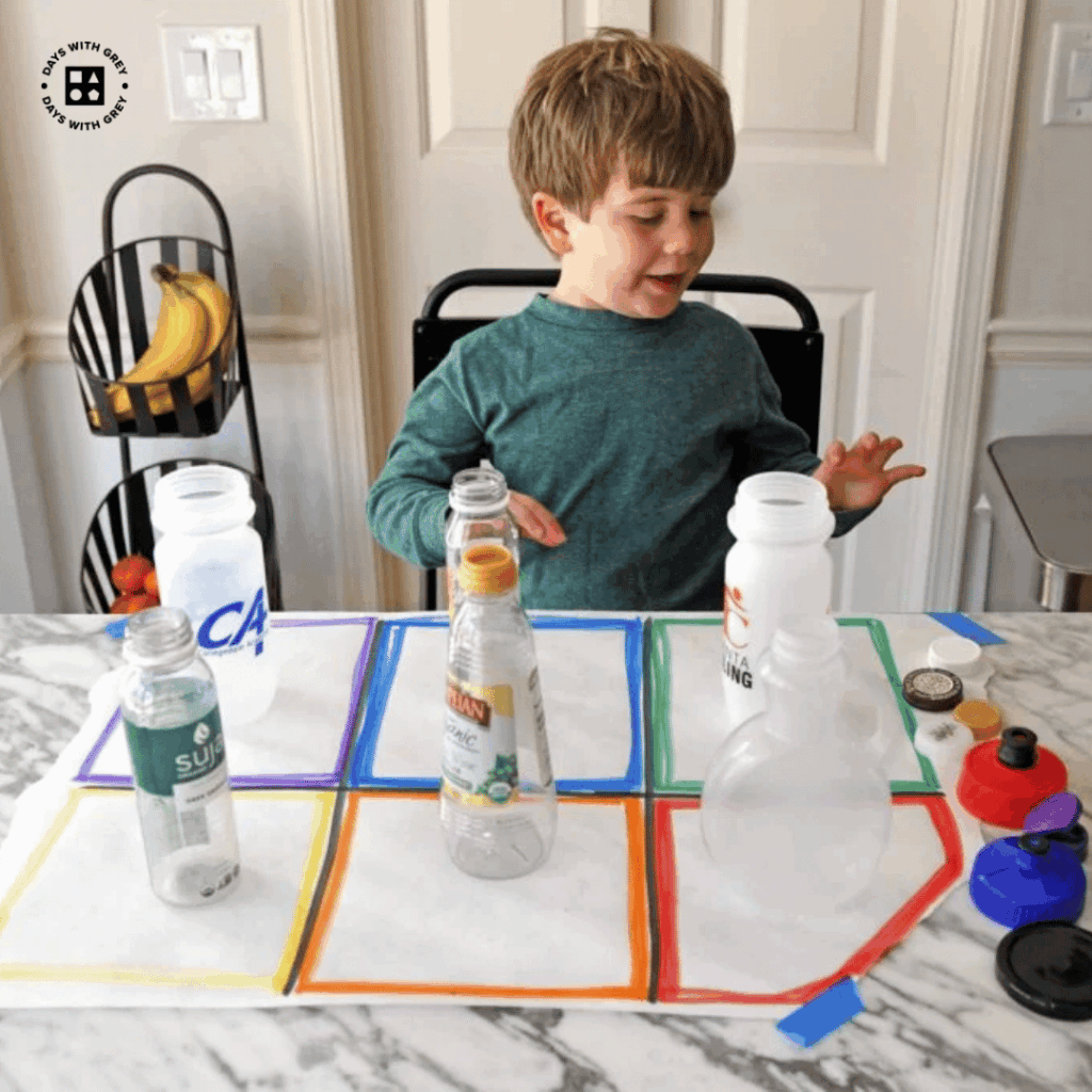 A young boy trying to match lids to the container on a table.