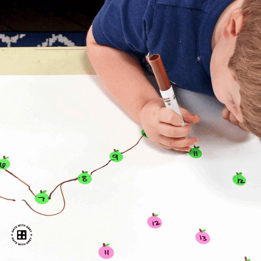 A young child using a marker to follow the dots on the paper.