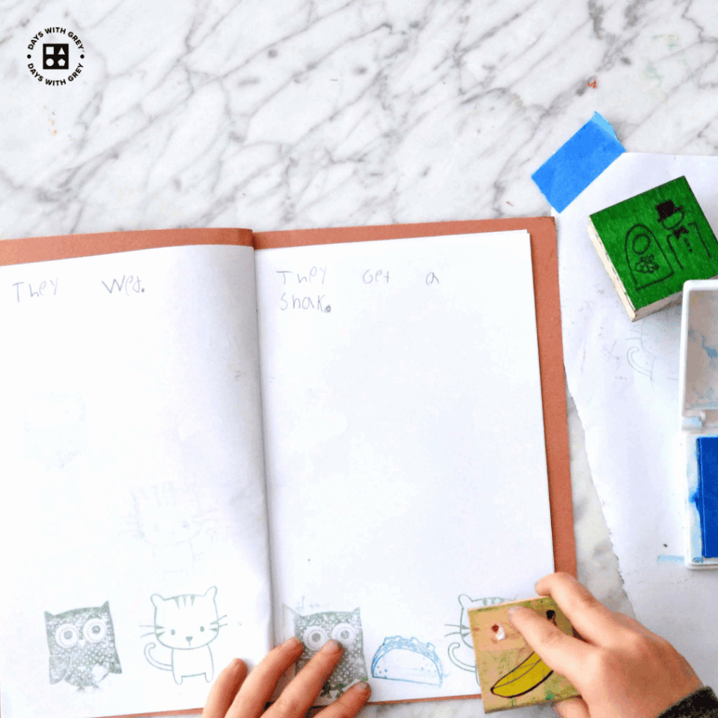 A kindergartener using stamps to make a story.